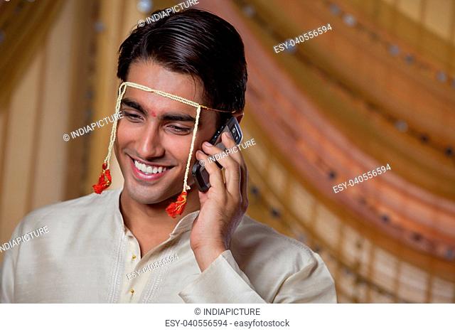 Smiling young groom talking on phone call