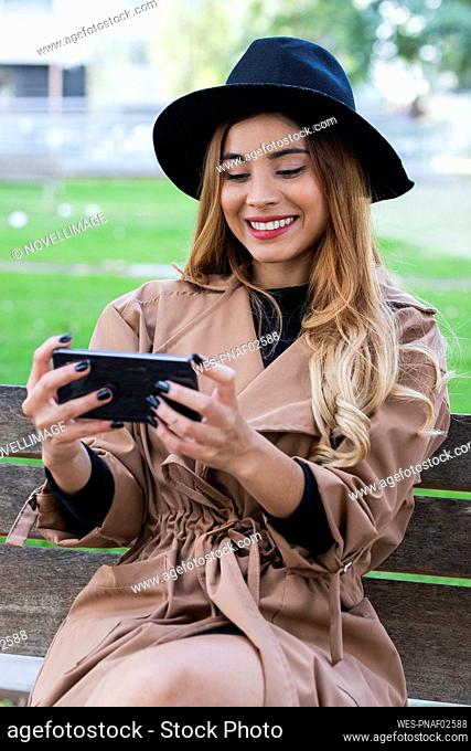 Smiling woman watching mobile phone on bench