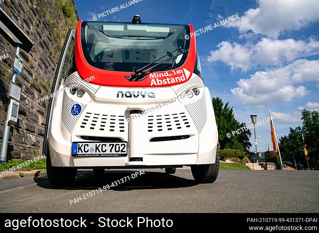 PRODUCTION - 10 July 2021, Bavaria, Kronach: An autonomous bus from the manufacturer Navya stands in front of the fortress wall in Kronach