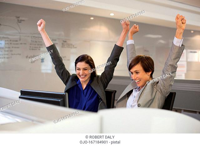 Enthusiastic businesswomen with arms raised in office