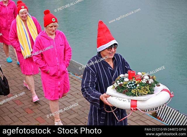 10 December 2023, Saxony-Anhalt, Osterwieck: Participants in the Advent swim enter the water with an Advent wreath at 6 degrees Celsius in the Osterwieck...