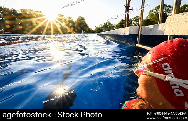 14 June 2023, Lower Saxony, Hanover: The rising sun is reflected in the swimming goggles of an early morning swimmer at the Annabad outdoor pool