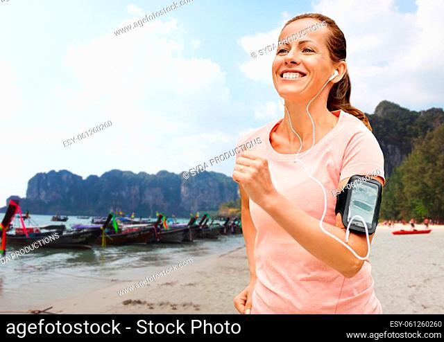 woman with earphones add armband jogging on beach