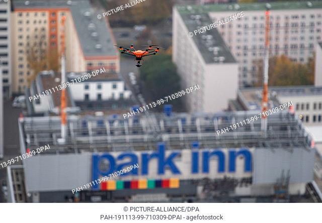 13 November 2019, Berlin: A drone flies through the air for a precise 3D measurement of the Berlin TV tower in front of the Park Inn Hotel