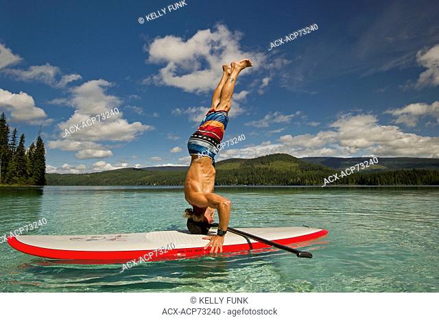 A paddle boarder practises yoga on the beautiful waters of Johnson Lake, North of Kamloops in the Thompson Okanagan region of British Columbia, Canada