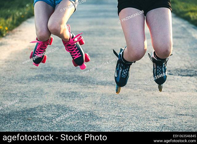 Teenage girls having fun rollerskating, jumping, spending time together on summer day