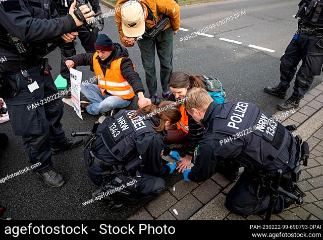 22 February 2023, North Rhine-Westphalia, Dortmund: Climate activists from the group Last Generation, who have taped their hands together to block a major road
