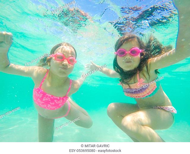 Funny children underwater portrait - Little girls wearing swimming goggles dive and swim in the seawater - Summer vacation fun