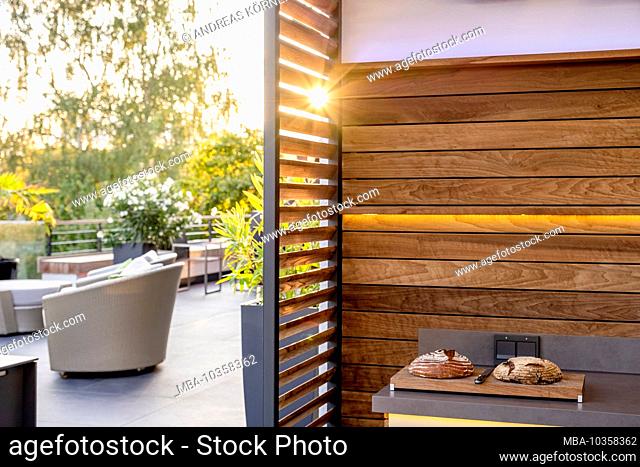 Outdoor kitchen in the evening light with freshly baked bread and seating area in the background