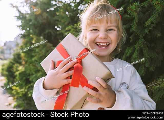 Cheerful girl holding Christmas gift box
