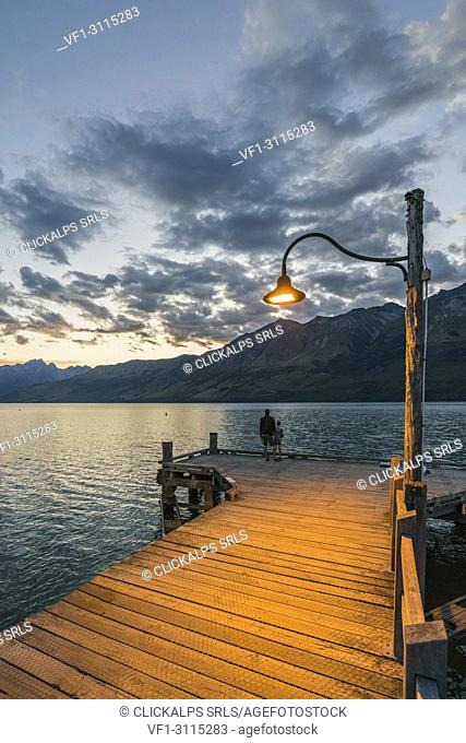 Man and child on the jetty at dusk. Glenorchy, Queenstown Lake district, Otago region, South Island, New Zealand