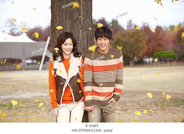 Young Couple Standing Under The Tree In Autumn