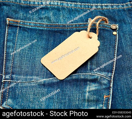 blank brown rectangular tag tied in the back pocket of blue folded jeans, top view