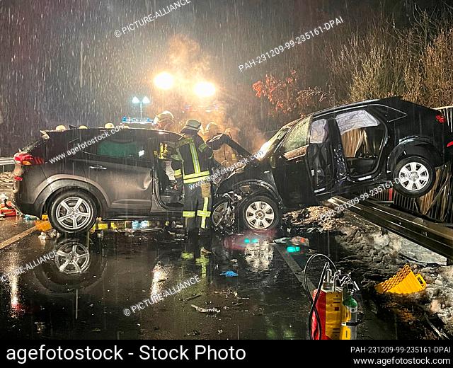 08 December 2023, Bavaria, Traitsching: Firefighters stand by two wrecked cars at the scene of the accident. Two people aged 53 and 54 died at the scene of a...