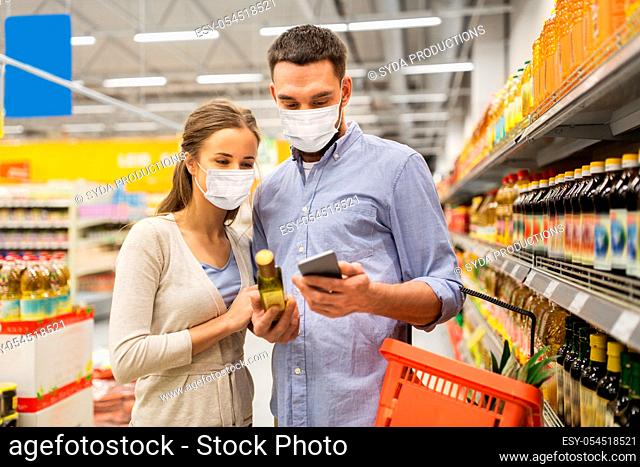 couple in masks with phone and olive oil at store