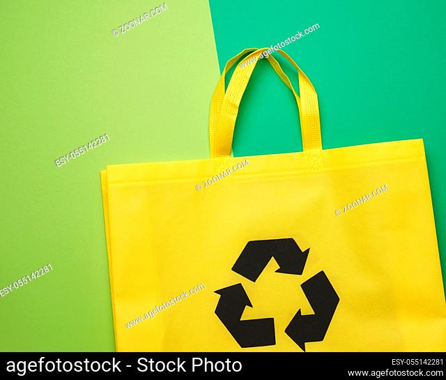 reusable yellow textile bag made of viscose on a green background. View from above, plastic rejection concept, zero waste