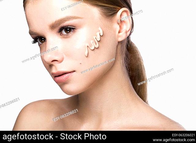 Beautiful young girl with tone cream on her skin. Beauty face. Picture taken in the studio on a white background