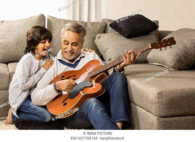 Grandfather teaching grandson to play the guitar