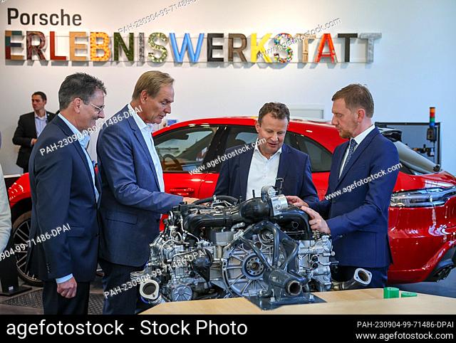 04 September 2023, Saxony, Leipzig: Gerd Rupp (2nd from right), Chairman of the Executive Board of Porsche Leipzig GmbH, explains a 4-cylinder boxer engine in...