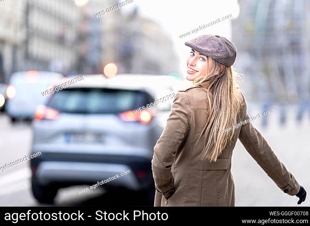 Beautiful woman looking over shoulder while standing on street