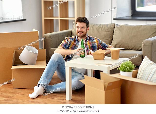 smiling man drinking beer and eating at new home