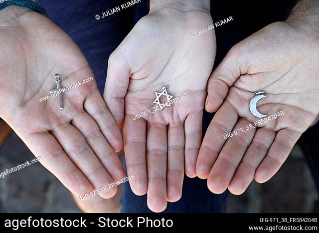 Young muslim, christian and jewish man showing religious symbols in France