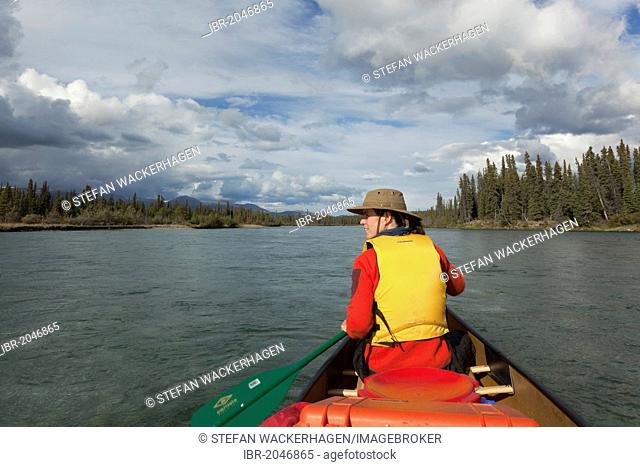 Young woman paddling a canoe, canoeing Takhini River, Yukon Territory, Canada
