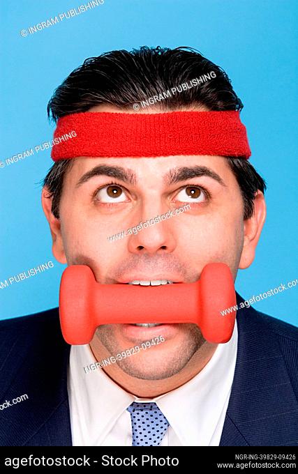 Businessman with a dumbbell in mouth