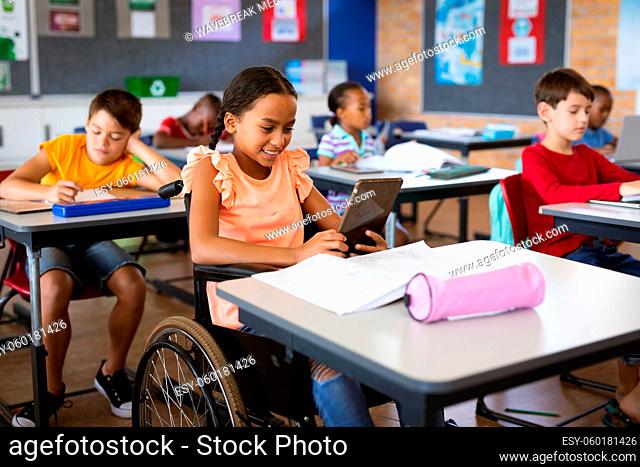 Disabled african american girl using digital tablet while sitting on wheelchair at elementary school