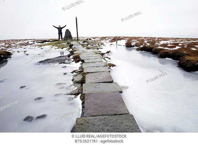 Top of the Buckden Pike, with a hiker celebrating the climing in a cold and frosty snowy day. Buckden, Upper Wharfedale, North Yorkshire, Yorshire Dales