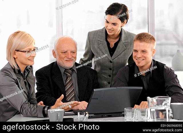 Smiling businessteam on meeting, mid-adult businesswoman showing computer work to coworkers