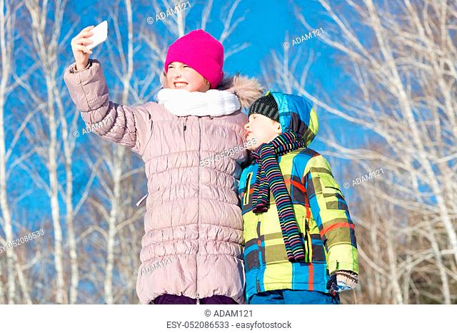Two happy kids making selfie photo in winter park