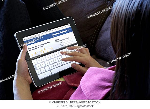 A woman relaxing while using iPad to check her Facebook page