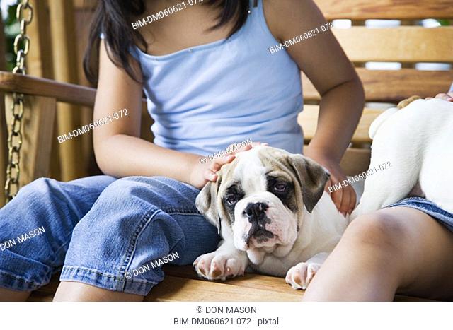 Girl petting puppy on porch swing