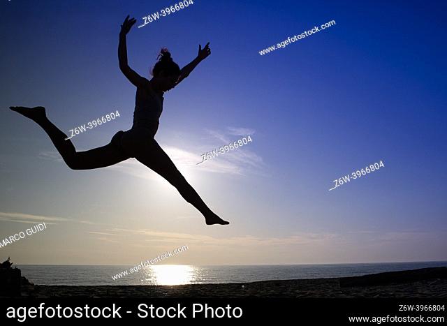 Photo shoot of a girl's jump performed outdoors against the light