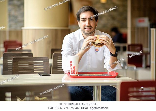 15 June 2018, Germany, Munich: Carlos Eduardo Baron, Burger King's manager in Germany, eats a burger during an interview. Photo: Matthias Balk/dpa