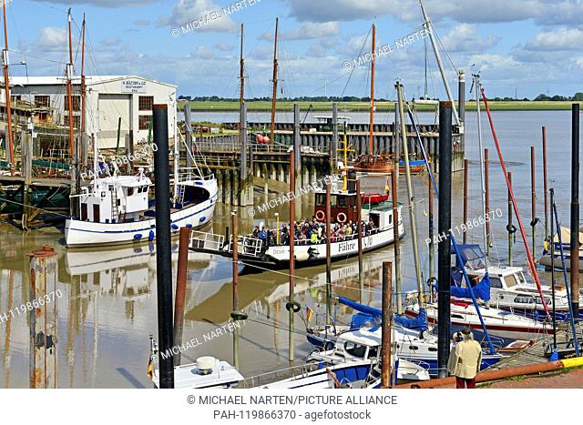 Ditzum's harbour beside the river Ems with boats and dolphins and the arriving small ferry from Petkum, 13 August 2017 | usage worldwide