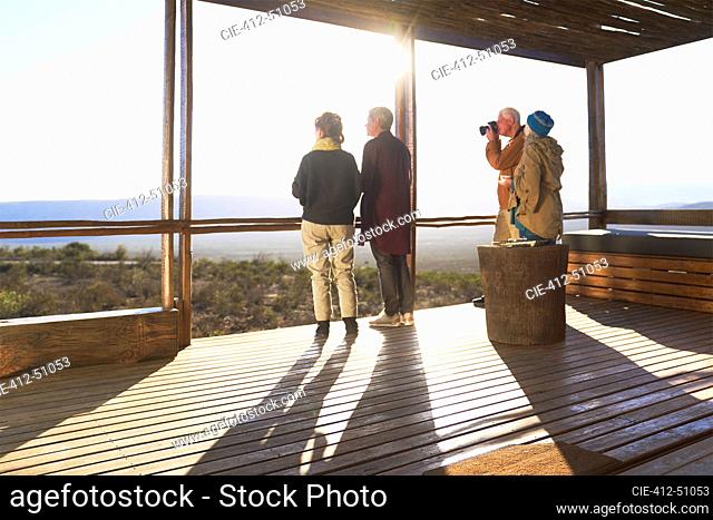 Friends looking at view from sunny safari lodge balcony