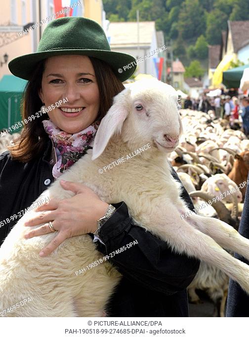18 May 2019, Bavaria, Mörnsheim: Michaela Kaniber, Minister of Agriculture in Bavaria (CSU), wears a traditional shepherd's garment and holds a lamb in her arms