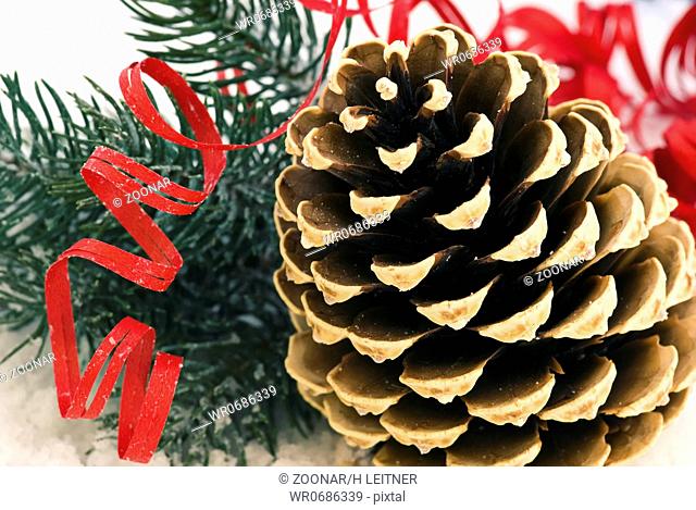 Pine cone with Christmas decoration as closeup in snow