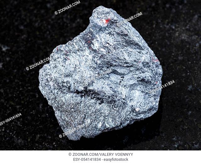 macro shooting of natural mineral rock specimen - raw antimony ore (Stibnite) stone on dark granite background from Ukraine