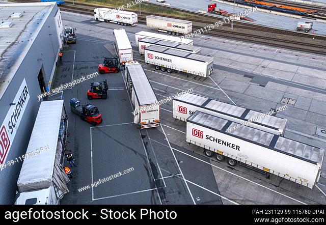 PRODUCTION - 21 November 2023, Mecklenburg-Western Pomerania, Rostock: Trucks of the logistics company DB Schenker are unloaded on the premises of the logistics...