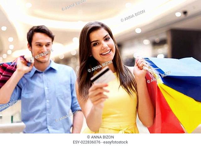 Happy woman holding credit card and shopping bags