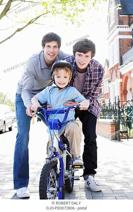 Father and sons with bicycle on sidewalk