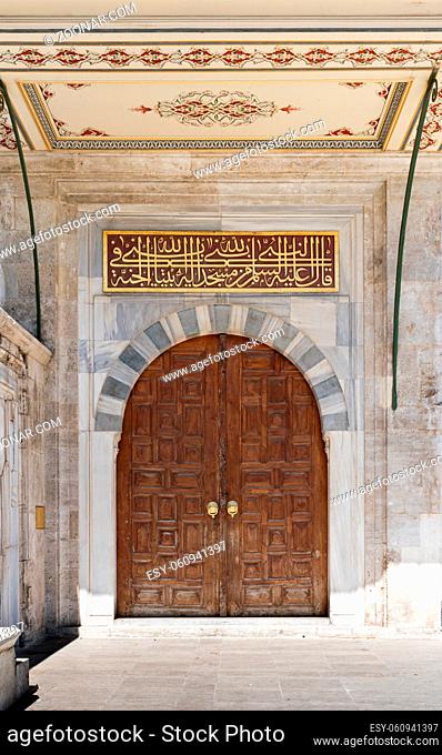 Wooden aged vaulted ornate door and stone wall at Sulaymaniye Mosque, Istanbul, Turkey