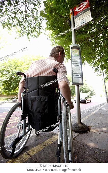 A disabled man in a wheelchair at a bus stop in London, England