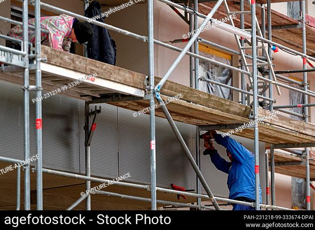 PRODUCTION - 15 December 2023, North Rhine-Westphalia, Mohnheim: Two men work on the balcony balustrades on the shell of the Sophie Scholl Quartier