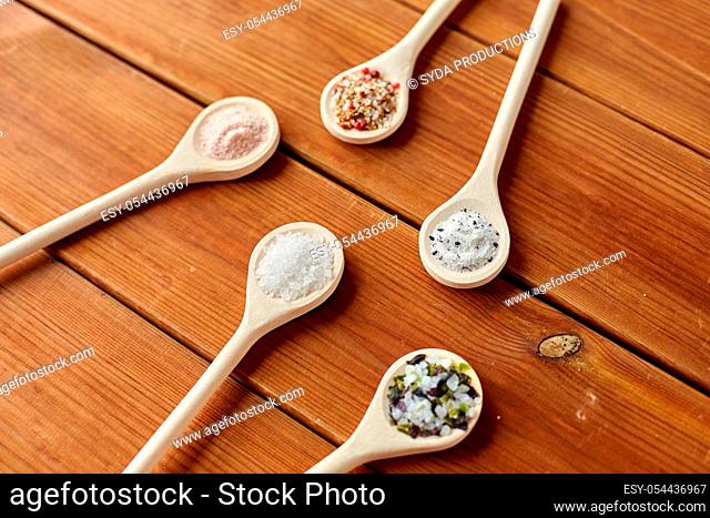 spoons with salt and spices on wooden table