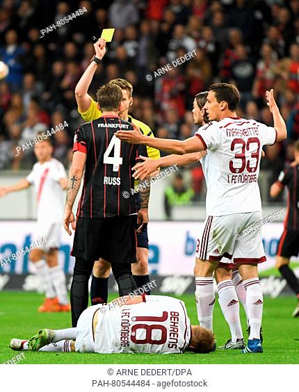 Frankfurt's Marco Russ (L) receives the yellow card by referee Daniel Siebert after a foul against Hanno Behrens (on the ground) during the German Bundesliga...