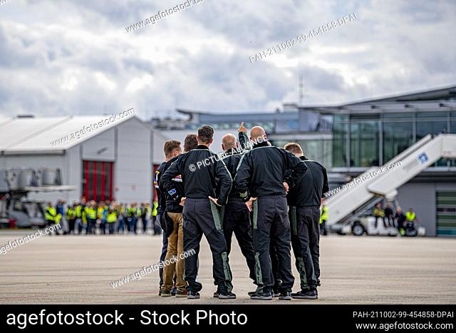 02 October 2021, North Rhine-Westphalia, Büren: The skydivers discuss before the start and look at the clouds in the sky